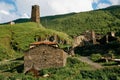 view of grassy field with old weathered rural buildings and hills on background, Ushguli, svaneti, Royalty Free Stock Photo